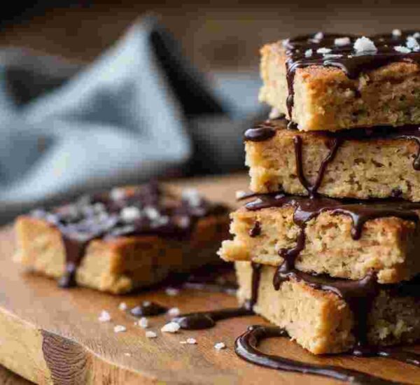 A square of chocolate flapjack with oats and a thick chocolate layer on top, cut and ready to eat.